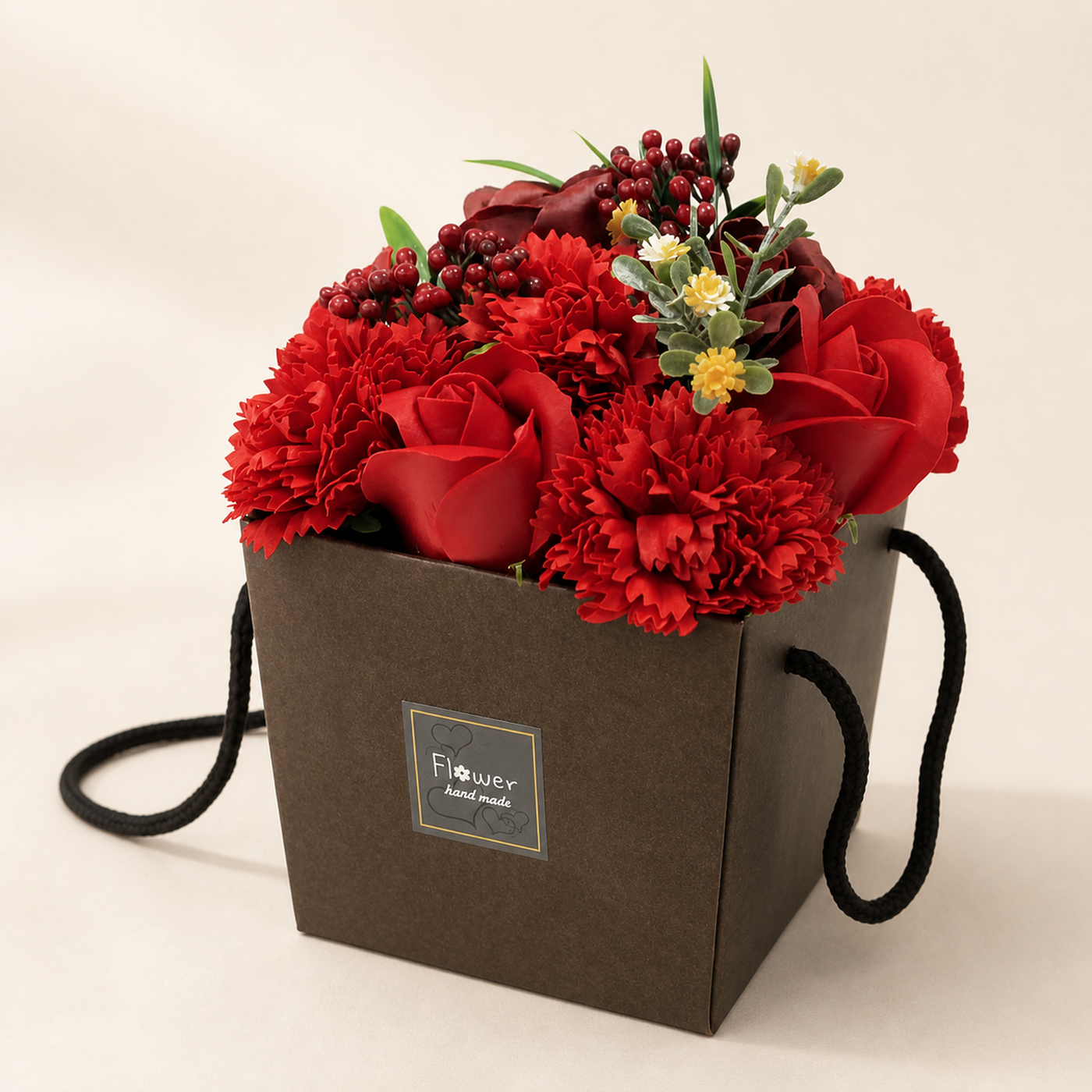 A soap flower bouquet of red roses and carnations in a black gift box