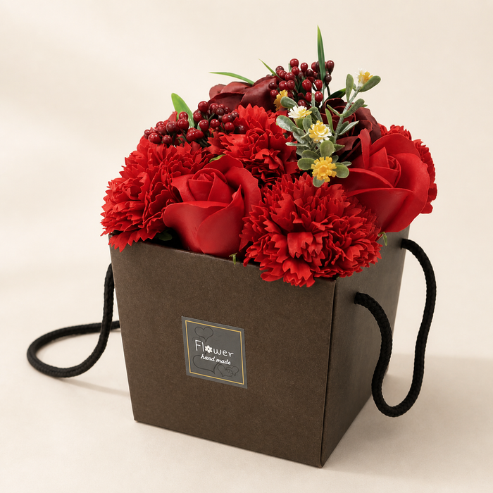 A soap flower bouquet of red roses and carnations in a black gift box